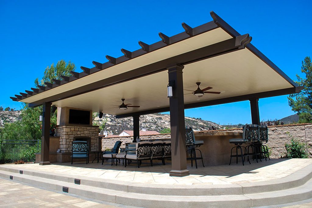 Freestanding Traditional Solid Patio Cover over an outdoor seating and dining area with a fireplace, tv, and patio furniture at a home in San Diego California