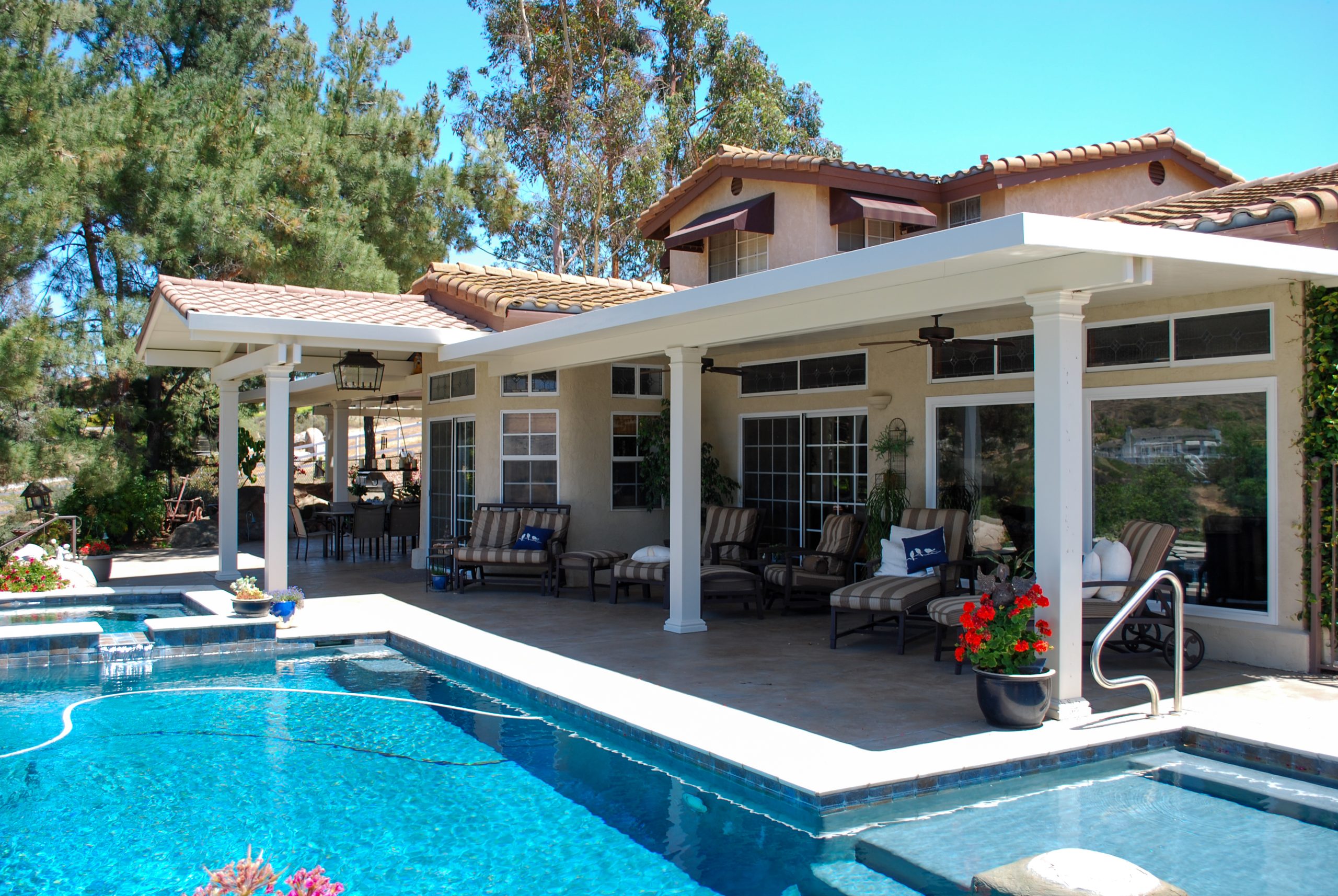Traditional style solid patio cover over an outdoor seating area next to a pool at a home in San Diego California
