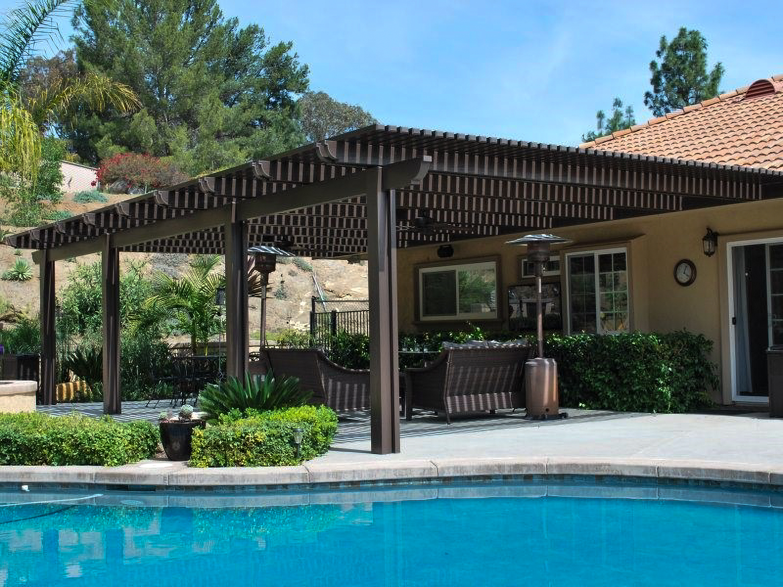 Traditional Style Lattice Patio Cover over an outdoor sitting area with furniture by a pool in a backyard of a San Diego California home